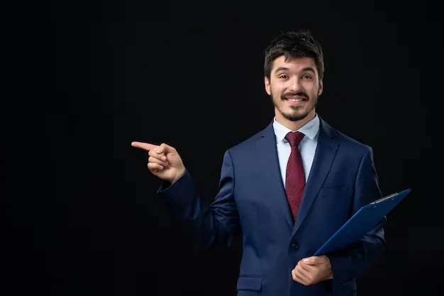 front-view-smiling-male-office-worker-suit-holding-documents-pointing-something-right-side-isolated-dark-wall_140725-97201.webp