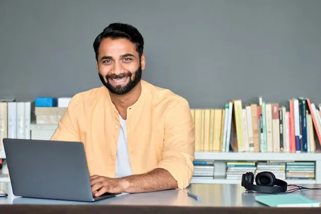 happy-indian-business-man-working-laptop-office-sitting-desk-portrait_562687-3159.webp