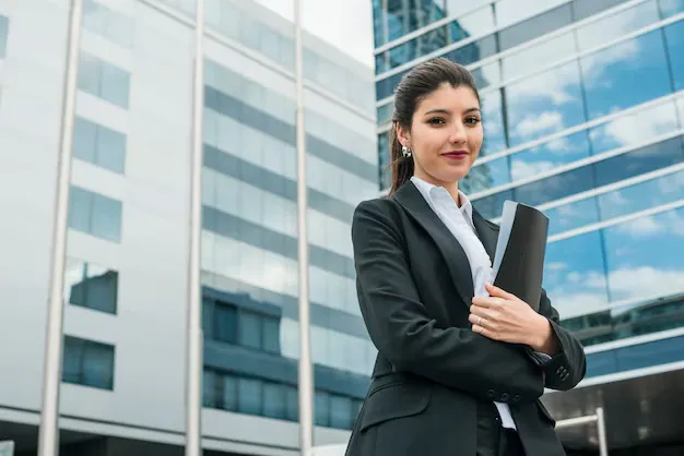 happy-young-businesswoman-holding-folder-standing-front-building_23-2148026710.webp