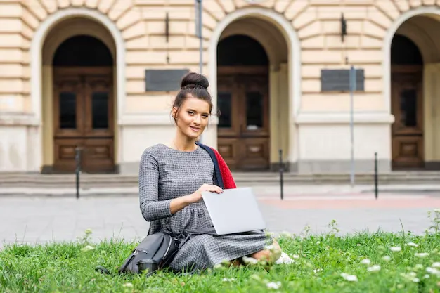 portrait-beautiful-young-smiling-student-studying-with-laptop-grass-near_141172-5443.webp