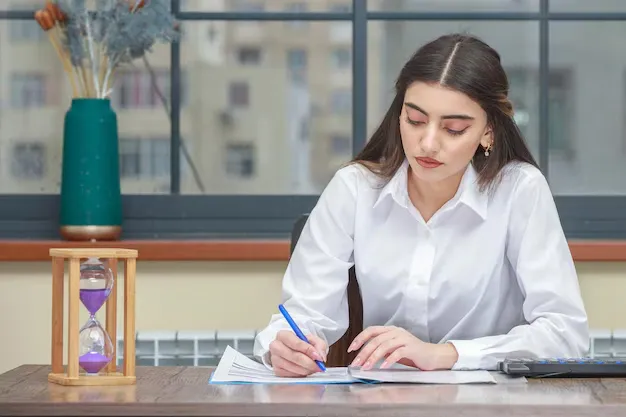 portrait-young-businesswoman-sitting-desk-writing-notes_144627-77463.webp