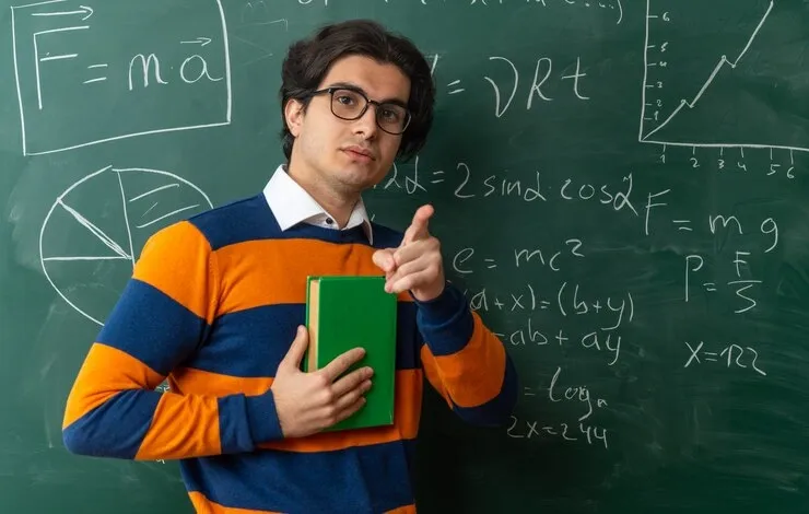serious-young-caucasian-geometry-teacher-wearing-glasses-standing-front-chalkboard-classroom-holding-book_141793-106363.webp