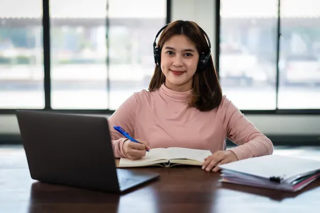 smiling-asian-girl-student-wears-wireless-headphones-write-notebook-study-language-online-watch-listen-lecturer-webinar-via-video-call-e-learning-home-distance-education_201468-1183.webp