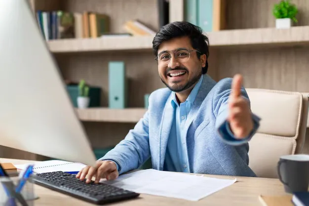 smiling-businessman-gives-thumbs-up-while-working-computer_922936-31087.webp