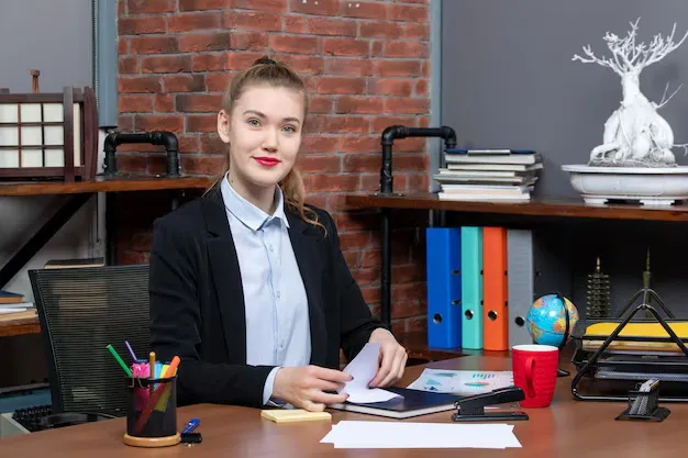 top-view-young-female-office-worker-sitting-her-desk-posing-camera_140725-106299.webp