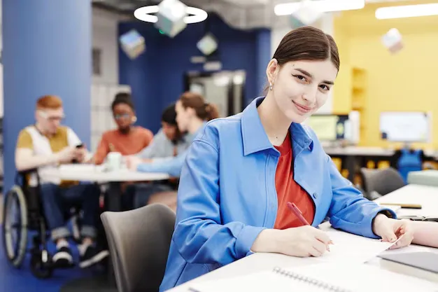 vibrant-portrait-young-woman-smiling-camera-while-taking-notes-college-library_236854-39193.webp