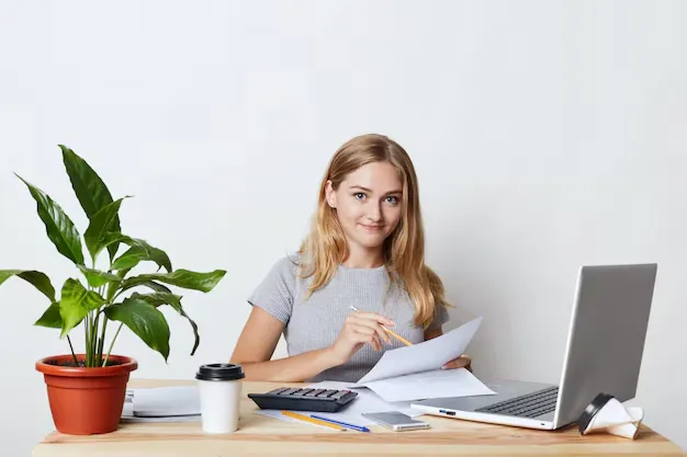 young-blonde-businesswoman-sitting-her-workplace-while-making-business-report-calculating-annual-figures-reading-documents-using-modern-technologies-her-work-drinking-takeaway-coffee_176532-6412.webp