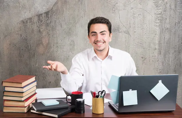 young-businessman-happily-looking-camera-office-desk_114579-28370.webp